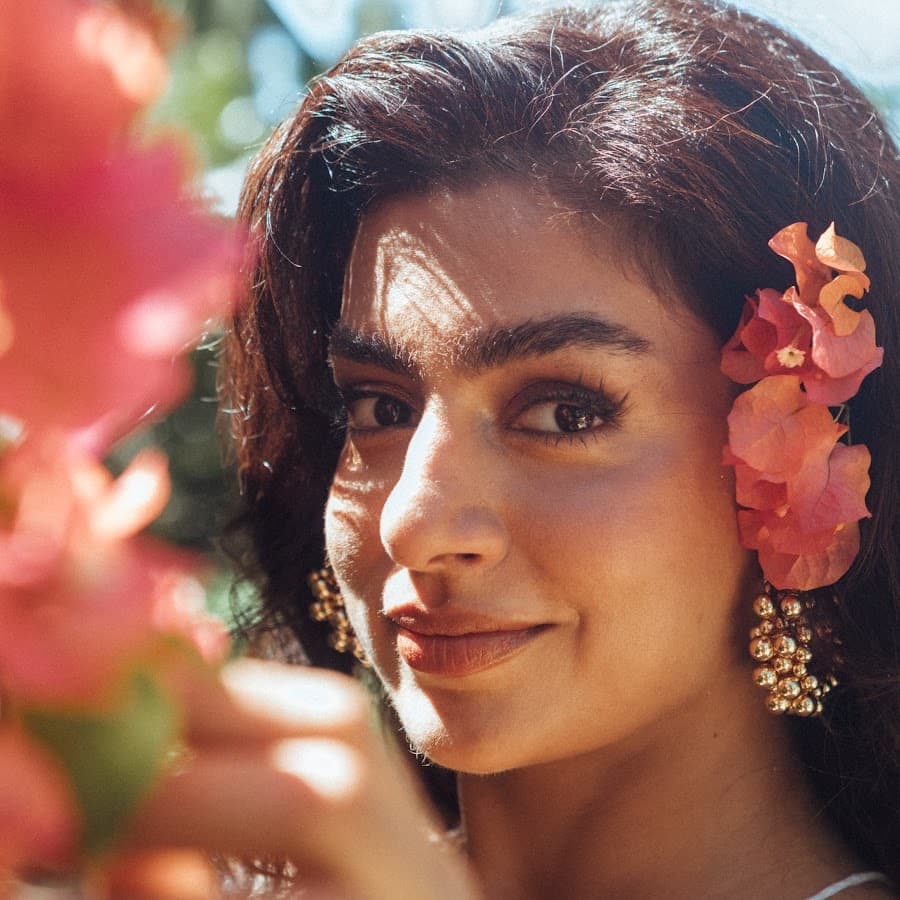 Angely with pink flowers in her hair, looking toward the camera